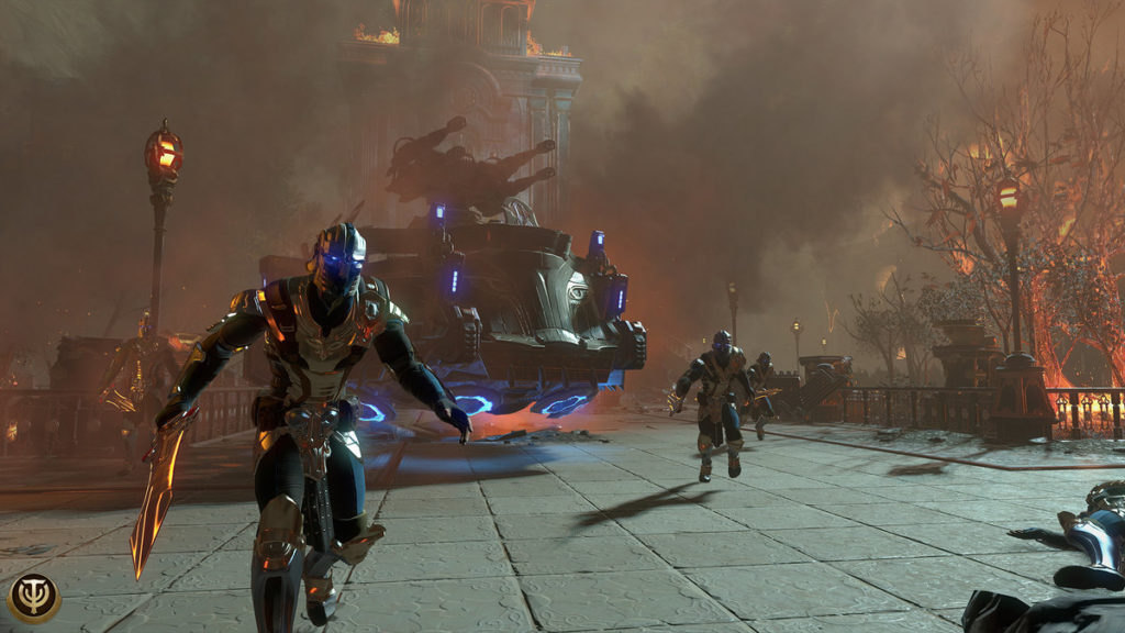 An Excerpt from the free MMORPG Skyforge is shown. In the picture you can see the characteristic landscape of the game and its characters: Three players in futuristic suits of armor and glowing swords are walking toward the camera. We see them in a long shot. The ground consists of stone tiles. On the right side of the image, a fenced park area can be seen in a crop with burning trees and a glowing lantern. Parts of the same park can also be seen on the left. Behind the game characters, a large black-blue glowing spaceship hovers above the stone ground. In the distance, the tower of a huge stone cathedral can be glimpsed in a large cloud of smoke.