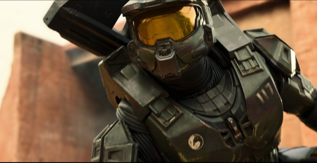 And once again the Spartans are fighting on the front lines as Halo season 2 on Paramount+ went into production. In this image, you can see the leader of the Spartans from the front in a close-up in battle dress and closed helmet, as he looks into the distance in front of him. In the background, a brown building facade can be recognized in a slight blur.