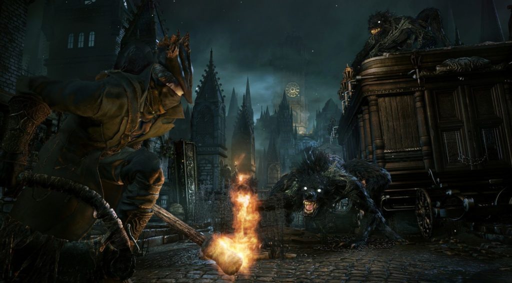 Here we see a screenshot from the game Bloodborne, which shows a boss fight. We see a very dark cobblestone street in the middle of a gloomy city at night with gothic-looking building facades and roofs. The protagonist and demon hunter is shown in the third-person perspective on the left side of the image. He has a dark gray cloak and hat on and is currently in a crouched position. In his left hand, he carries a burning torch, and in his right hand a kind of huge scythe. His gaze falls on a huge, black werewolf with a white-open mouth, sharp teeth, and bright white eyes staring back at him. This game is very popular among Souls-like games.