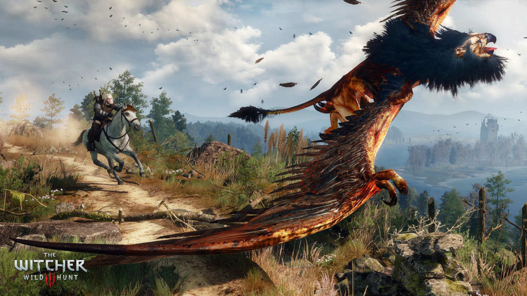 Are you looking for the best Souls game? Then The Witcher 3 might be just the thing for you. Here we see a screenshot from the game with the protagonist on his horse shown in a long shot, galloping along a narrow path on the left, kicking up dust behind him. The path runs from the top left to the front right of the image. On the right side, a wide valley with blue lakes and islands with numerous trees can be seen in light haze and behind it, the mountains open up. In the front left of the picture, there is a flying mythical creature that looks like a mixture of a bird and a lion. It has a reddish coloring and has both fur and feathers. Above it, we see the blue sky covered with clouds.