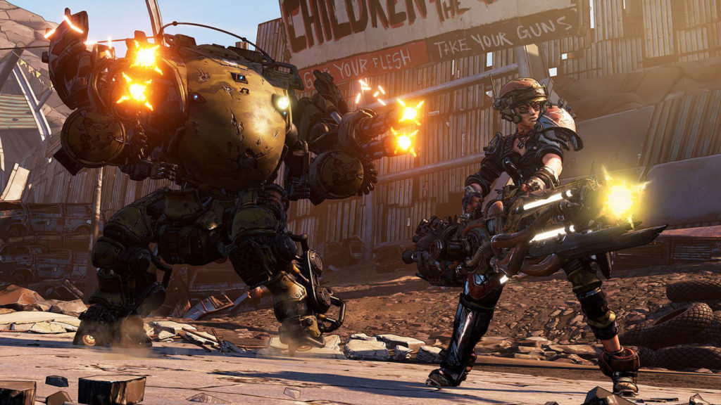 This screenshot from the game Borderlands 3 shows a combat robot and a player in combat gear with a minigun in a long shot in daylight. Both open fire and look past the viewer on the right. They are standing on a stone floor and in the background a slanted high fence made of corrugated metal can be seen, on which the following two sentences can be read in white capital letters on a sign: "Give your flesh, take your guns". This game is one of the very good 2 player PS5 games.