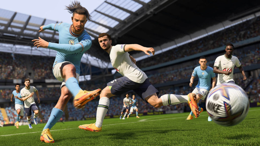 Play digital soccer in FIFA 23, one of the best 2 player PS5 games. This cover from the game impressively shows an intense soccer match. In a long shot on the left side, a southern player with wide pants, a light blue jersey, and a black pigtail can be seen in a slightly oblique perspective in the bottom view. He has just kicked the ball, which is shown in motion blur in the lower left of the picture in the air above the green artificial turf. On the right, directly behind him, an opposing player in black pants, a white jersey, and black short hair jumps through the picture. His gaze falls on the ball. Behind the two players, other players in white and blue jerseys are shown running after the ball. In the blur, we catch a glimpse of the huge grandstand filled with spectators.