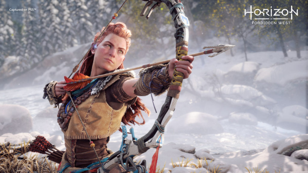 Here we can see a screenshot from Zero Dawn. In the picture, we see the female protagonist on the left of the image in the semi-close-up with a bow and arrow in front of a winter landscape during the day. She looks to the right of the picture with her bow stretched and has leathery clothing and red bundled long hair. A Horizon MMO is said to have been commissioned by Sony.