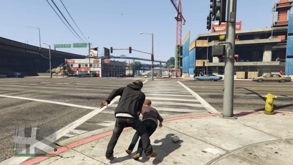 Run through a huge game world in GTA V, as seen in this screenshot: In third-person view, the player is shown in a long shot centered in the lower half of the screen, just as he bumps into a brown-haired person with a brown pullover and black pants on a sidewalk at a large crossroads in daylight, causing him to fall to the ground. The player himself is wearing black jeans, a black hoodie, and a brown baseball cap. In the back right of the picture is a stone parking garage. Next to it is a red crane. To the left in the background is a department store with a white and red facade, and to the left of it, a highway runs from the foreground to the background toward the center. Grand Theft Auto V is one of the best multiplayer PS5 games.
