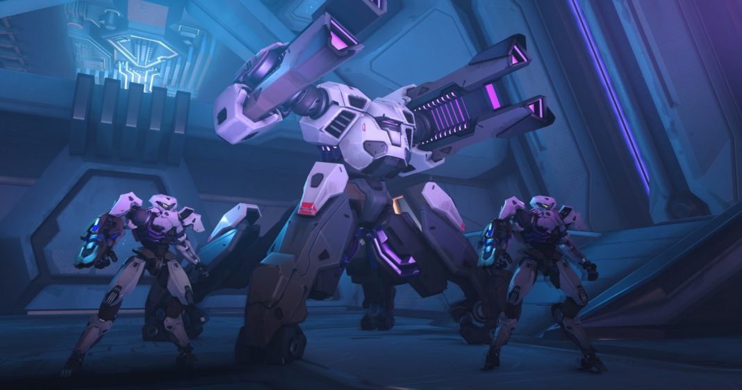 Overwatch 2 is one of the best PS5 multiplayer games. In this screenshot, we see three combat robots on standby in a spaceship-like room, which is illuminated in bluish-purple. In the center of the image, in half-profile, is a very tall white and black robot with two powerful cannon barrels. To the left and right of him are two small robots in the same posture and color. In the background, blue light shines through a hole.