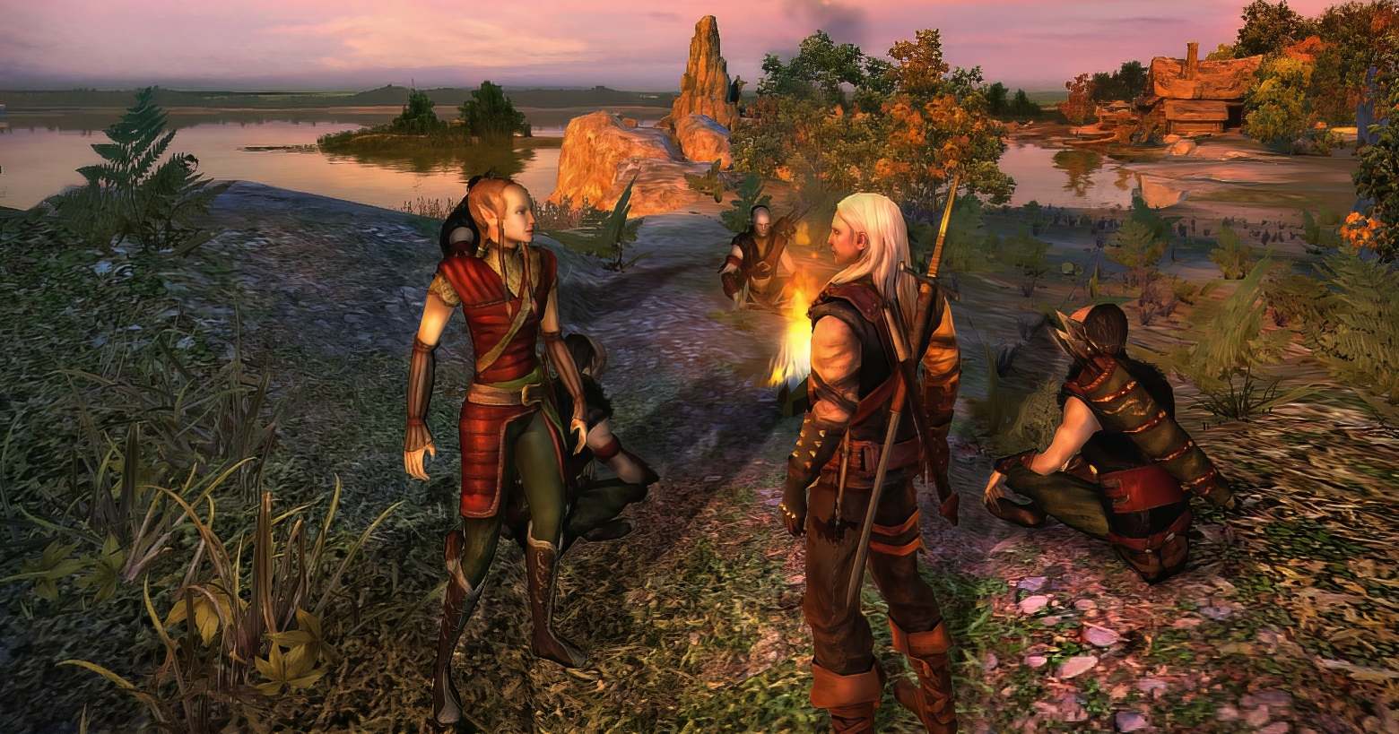 In this screenshot of the first installment, we are looking at a grass-covered rocky coast slightly from above. The dusk bathes the scene in a warm orange tone. A large lake is depicted in the background and a brown, large wooden house stands in the right background. In the foreground, we see Gerald in the third person in a long shot, standing at a campfire with three other characters.