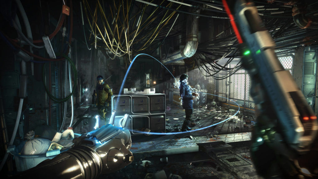 Sneak up on your opponents and kill them with impressive skills, as seen here in this screenshot: As the protagonist, we look into a black room in first-person perspective, where numerous cables run along the ceiling and partially hang down. The room is very elongated and leads strongly into the background of the image. On the left, many cables also run along the wall. On the right, a large grid can be seen, through which daylight falls into the room. In the middle of the room are several stacked metal boxes and there is a lot of garbage on the dark floor. In front of the protagonist, two enemy soldiers stand at some distance. The left soldier is male and wears a green uniform. On the right is a female soldier in a blue uniform. With our left glove, we form a fist so that two blue light beams shoot out and electrocute the female soldier. In our right hand, we hold up a silver pistol with a laser pointer, which can be seen in the motion blur on the right.