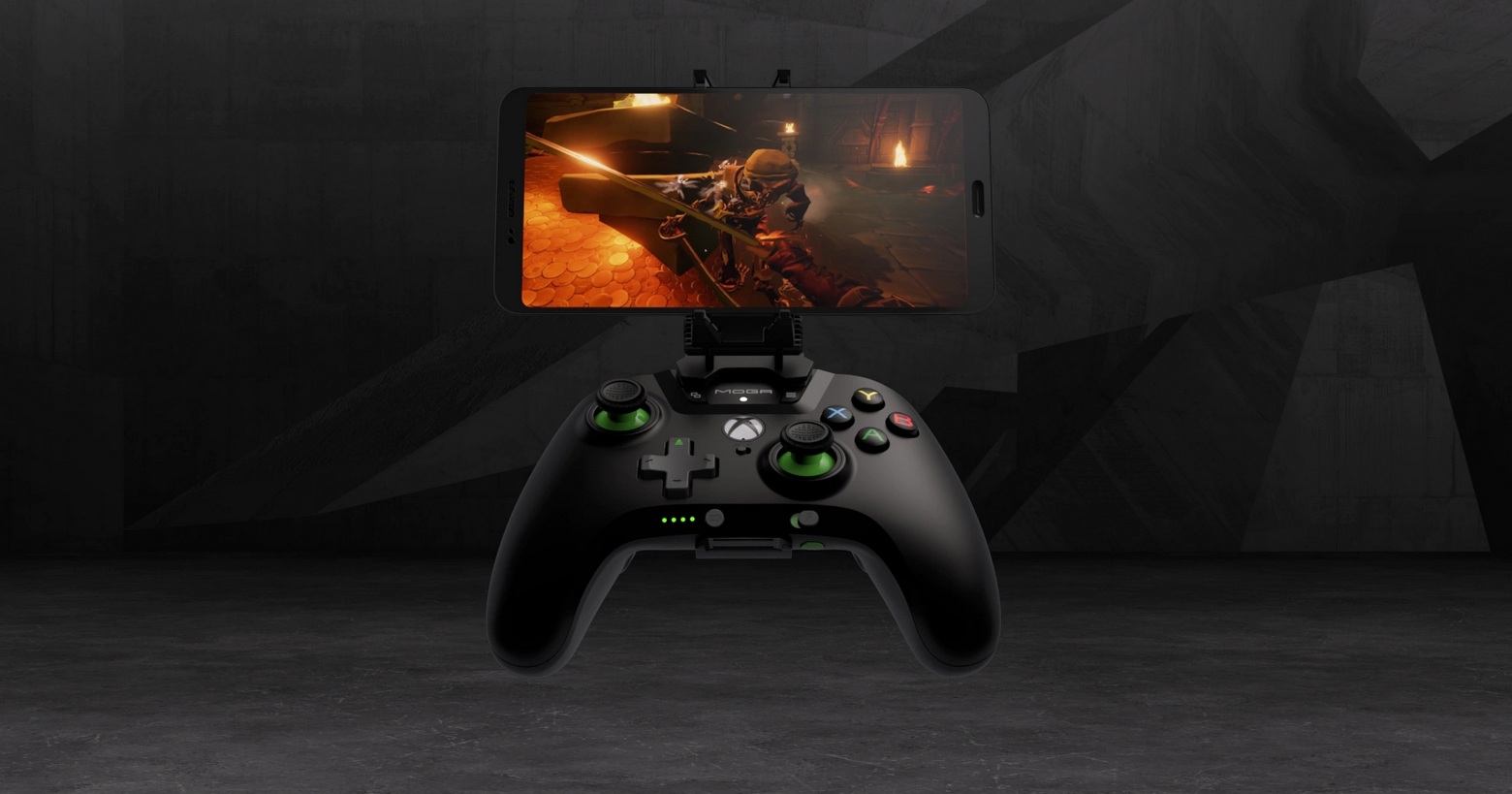 Here we see a controller from Xbox with a smartphone mounted in front of a dark background. In this way, the controller can be connected to the cell phone via Bluetooth and numerous games can be played via Microsoft's streaming service. An action FPS title can be seen on the cell phone. The background consists of a dark gray concrete-like space with angled lines and shapes. The controller has a black color and a curved ergonomic shape with the typical Xbox logo in white in the center. The two joysticks have a green base and on the right side of the controller we see the typical colorful buttons "X, Y, A, B". The game seen on the phone is a screenshot from a medieval first-person action adventure and the player is currently in a sword duel with a knight in a fiery place.