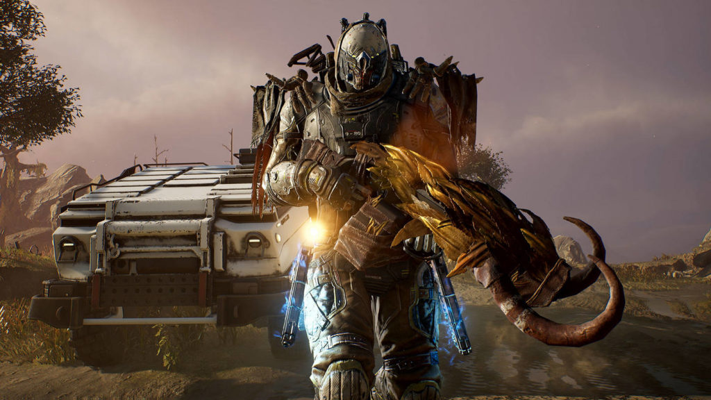 In the foreground of this screenshot of Outriders, a playable character can be seen in half-total from the front. He wears a steampunk-like leather combat suit and has a wooden construction on his back. He wears a strange mask that covers almost his entire face. On the left and right side of his legs, he has holstered two blue flashing pistols and he holds a very futuristic looking Rifle with golden ornamentation and two horns in his hands. Calmly he strides towards us. In the background, to the left of him, the rear of a white armored jeep can be seen. We are on an alien planet in a stony landscape during the day, and we can see a tree and a mountain range to the left. With Outriders, you play a wild loot shooter and one of the most exciting 2 player PS5 games.