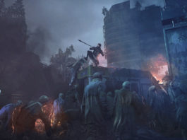In this screenshot from Dying Light 2: Stay Human, we see the player in the center of the screen, armed with a spear, in a long shot in a gloomy post-apocalyptic city. He is standing on an abandoned ambulance overgrown with plants and is kicking down a zombie that is climbing up. The entire image is shrouded in smoke and we can make out isolated buildings in the clouds of smoke. In the background, a skyscraper is on fire. In the foreground, numerous zombies stand around the ambulance, trying to reach the player. This title is one of the best scary games to play with friends and one of the most sought-after co-op horror games today.