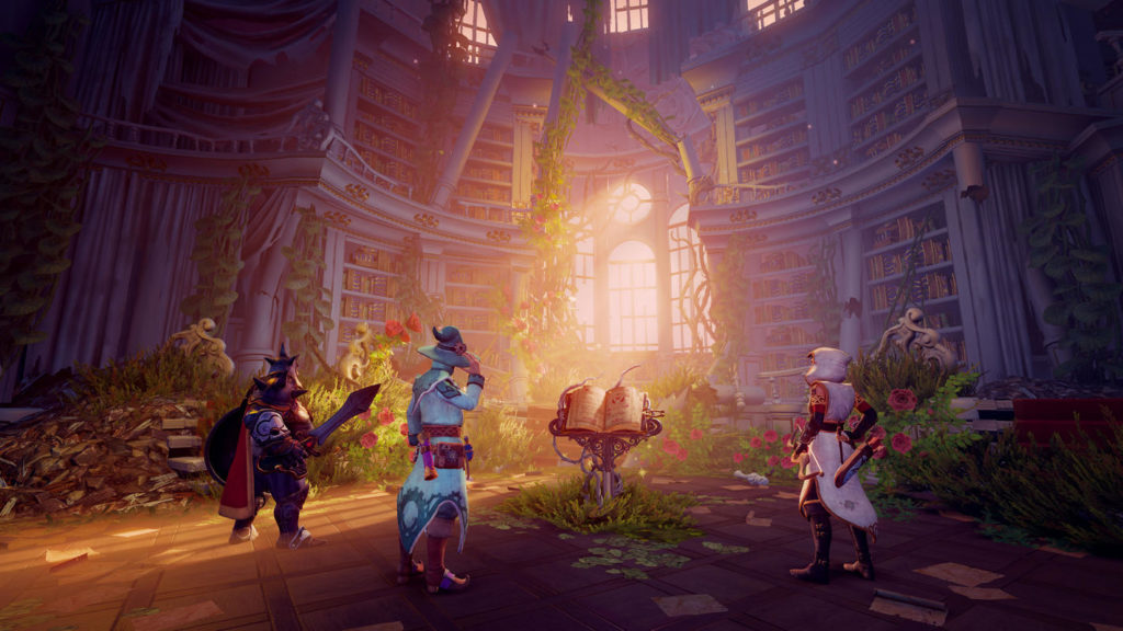 In this screenshot from Trine 4: The Nightmare Prince, we see the three main characters from behind, as they stand in the center of the image in a huge enchanted library around a writing desk. A large yellow-leafed book is open on the desk, which is illuminated by a bright warm light that falls through a large very historic-looking window front. Otherwise, the hall is quite dark. In the background and around the writing desk we see many green plants with red flowers and there are many writing sheets on the stone floor. The player on the left is a knight with a big sword and a red cape. In the middle stands a wizard in a mint-colored robe and hat of the same color. On the right stands a thief in a white robe and white hood.