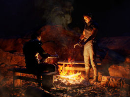 A playable teaser was released for the Gothic remake, in which gamers could already try out the gameplay and admire the graphics, as seen here in the screenshot: Two male characters dressed in medieval style are shown in the middle of the night in a long shot in front of a campfire. They are in the center of the image. The person on the left is sitting on a wooden bench and is preparing a meal with a knife. The person on the right is standing by the campfire and has both his hands stretched out over it to warm them. The fire lights up the otherwise dark place with a reddish-yellow tone. Release date of the new Gothic Game is supposed to be December 2023 for PS5.