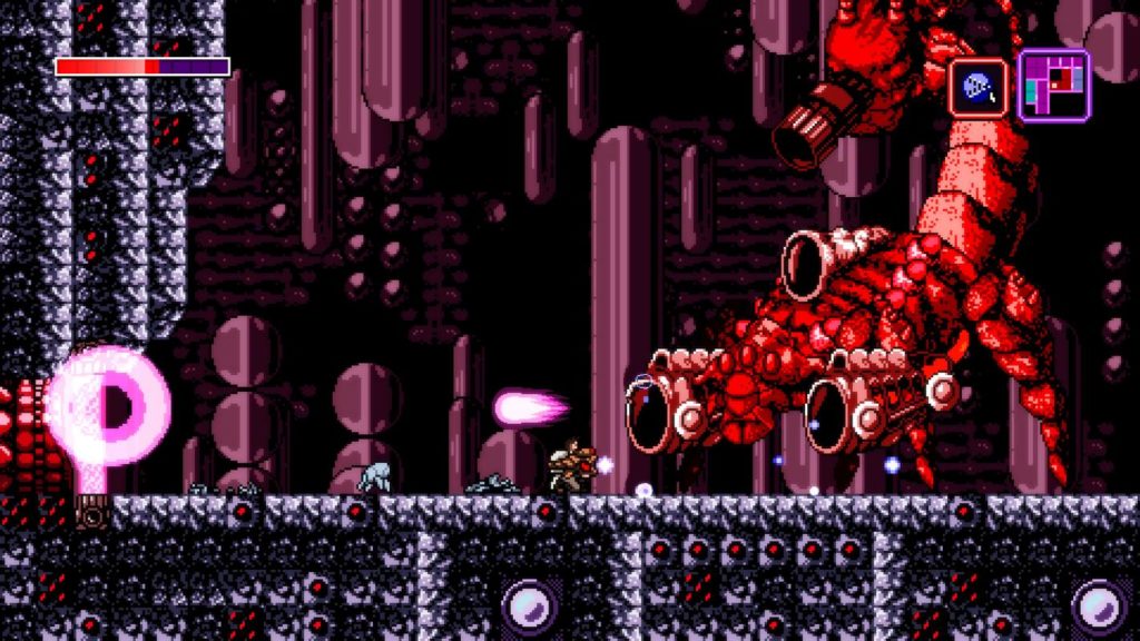 A screenshot of the 2D sidescroller Axiom Verge can be seen. The protagonist is shown crouched in a long shot centered on the bottom half of the image finding himself in a kind of dark dungeon. He wears white clothing, has brown hair, and has a large red-brown colored alien-like weapon in his hand, with which he shoots at a giant red scorpion shown on the right of the image. The scorpion shoots pink fireballs from one of its four cannon barrels, one of which is located at the end of its upturned tail and aimed at the player. The game foreground consists of rock-like black and white pixelated blocks, which have occasional red dots in the center. In the distance, horizontally arranged round to spherical shapes can be seen in dark red color against a black background. This title is known as one of the best Metroidvania games on Switch.
