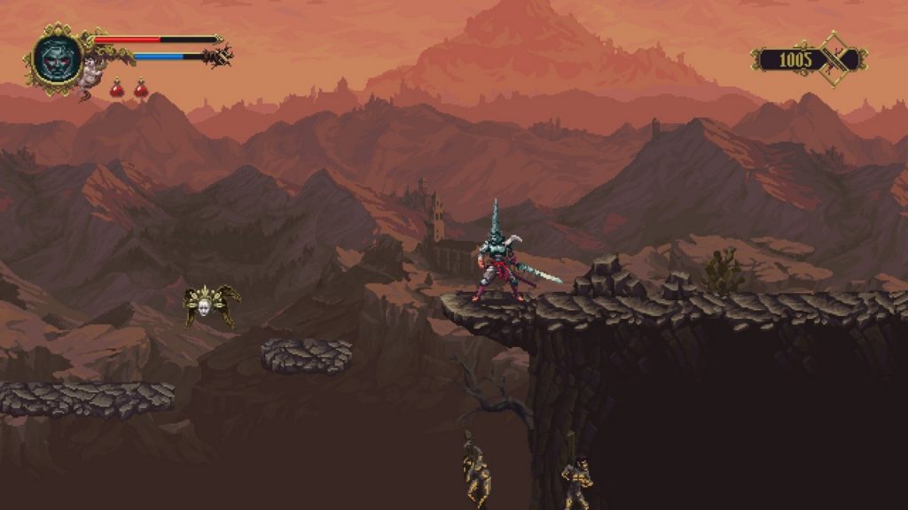In 2D sidescroller graphics, this screenshot from Blasphemous shows the protagonist in the center of the image in a long shot. He stands on a brownish ledge and looks to the left. In his left hand, he holds a longsword and wears iron armor and an iron helmet, which is very long and pointed upwards. Around his waist, he wears a red cloth garment. A little further to the left, brown rock platforms are depicted floating in the air, onto which the protagonist must jump. On the left, a spidery figure with a historical-looking yellow head hovers above the stone platforms. Below the main character, two corpses can be seen impaled on a tree. In the distant background, we see a vast mountain range with pointed mountains that take up the entire frame and are illuminated reddish by the setting sun.