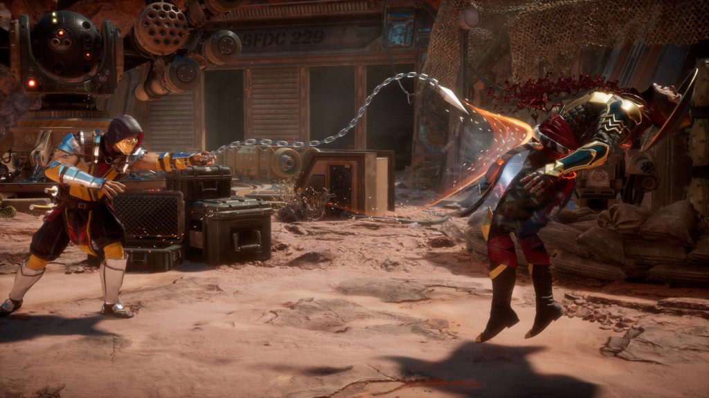 From a perspective view, this screenshot from Mortal Kombat 11 shows two characters in half-profile in a long shot, fighting each other in a very sandy steampunk-like battle arena outside in daylight. The character on the left has a black and orange battle suit with a black hood pulled over his head. His mouth is covered with an orange mask. He is leaning forward and has thrown a huge metallic chain with many links and a spike at the end at his opponent, which runs horizontally through the image in a snake shape. With the chain he just hit the opponent, causing dark red blood to spurt out of him. The character on the right is lifted a bit into the air by this, his gaze going up to the sky, distorted with pain. He has a red combat uniform and a round, tapered, metallic Asian hat. In the background is an orange-brown house facade with large black windows, in front of which various hard cases and crates are lying. To the upper left of the building, we see a huge futuristic turret facing us. Without a doubt, this game is one of the best fighting games for PC.