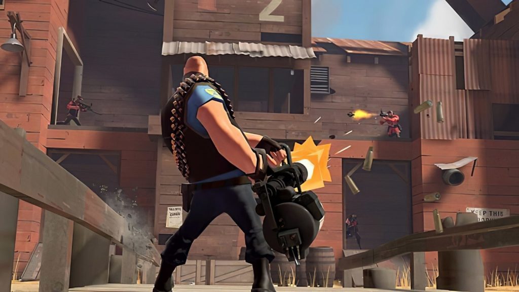 The humorous comic shooter is still one of the best fps games, as this screenshot illustrates: In the bottom view, we look at a player in a long shot in the role of heavy gunner with blue coloring and bald head. He is armed with a huge minigun and is standing in the middle of the image on a wooden bridge during the day. He is currently shooting at another player of the red opposing team, who is simultaneously firing a missile at him. The enemy is on top of a huge wooden reddish-brown building complex, which consists of countless nooks, openings, and opportunities for cover. At the bottom right and top left we spot more players of the red team.