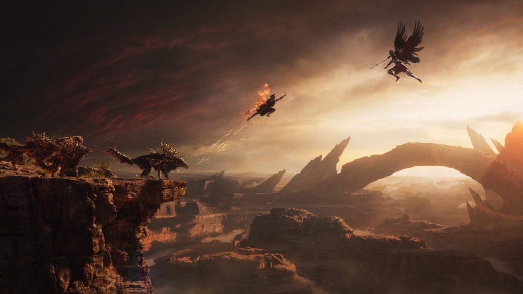 The question of the release date for Forspoken is now finally settled. In this screenshot, we see Frey from the side and in a long shot in the center of the screen. She is jumping from a ledge at a 45-degree angle upwards to the right in the direction of a flying human-like creature with big wings and a spear in its hand. On the ledge to the left are three wolf-like creatures covered with some kind of branches. In the background, a gigantic round rock archway is depicted on the right side, and the rest of the landscape is equally rocky and brown. Behind the archway, the evening sun shines through and gives the scene a warm tone. All the creatures and characters shown appear almost as black silhouettes due to the backlight, which has a very cinematic effect.