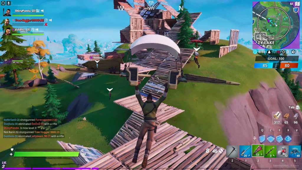 This screenshot again shows the player with black skin as in the first screenshot. He just lands with a white-brown parachute construction on a wooden floor, which we see at the bottom center of the image in the crop. The erected wooden structure continues centrally into the background, then goes up a mountain with many ramps, and then rises even higher into the sky. Finally, the wooden structure rises out of the top center of the image in the background. To the left and right of the wooden structure walk Suad members marked with a white triangle over their heads. In addition to the grassy hill in the center, we also glimpse a continuing grassy plain on the left, where two green fir trees and a yellow-leaved tree can be seen. In the distance, a similar landscape can be seen, but it is in the storm, so the background is completely colored turquoise.