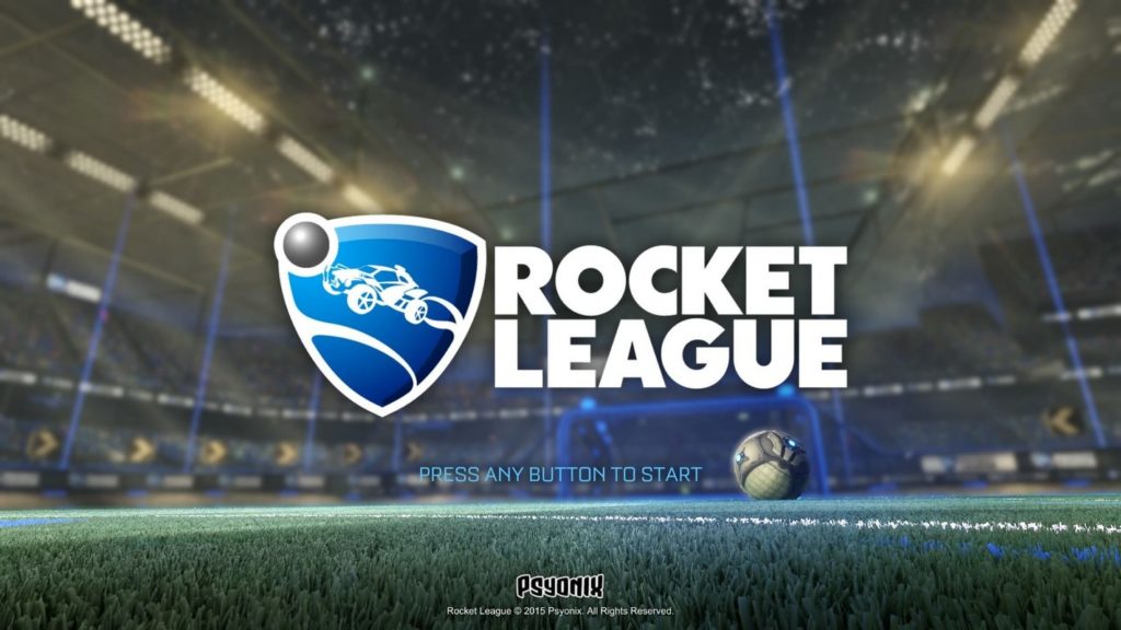 In your search for special games for the PlayStation 5, you should check out Rocket League, which is one of the most original PS5 split screen games. On this cove, the brand of the game is positioned in the center of the image. In white capital letters we read "Rocket League" and to the left of it we see the blue and white logo that looks like a triangular shield. On it we see a stylized racing car kicking a ball. The ball is shown in gray in the logo at the top left. We look up from a lower perspective of a soccer field with artificial turf and see in the background in the blur a huge grandstand with many yellow lights on the ceiling.
