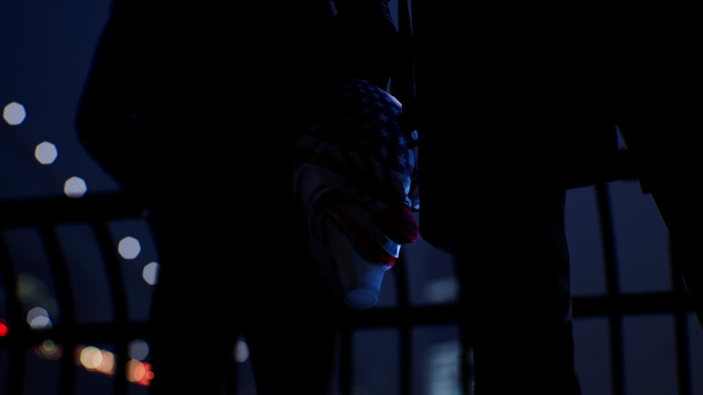 In the center of the image, we can see one of the four masks from the new heist simulation, slightly hidden. It is the one with the American flag as a motif. It is attached to the jacket of one of the main characters, who is standing next to another person. Both of them have their backs turned to us and we can only see them in the cut since we are looking at the action at the level of the mask and are standing quite close to the characters. They are at a railing and behind them, we can see the East River in front of New York. at night.
