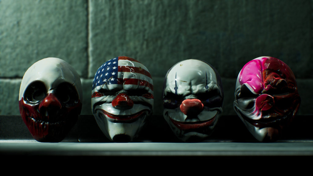 This screenshot shows a close-up of all four masks of the well-known main characters, which will get to see again in Payday 3. They are shown from the front, as they are draped in a row on a shelf and look at us with their nasty grimaces and bright colors. The left mask has a half-white and half-red pattern, the second from the left has the American flag as a motif, to the right is another red and white mask, and to the far right is a white and pink mask with a conspicuously flattened nose.