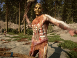 The player stands in first-person perspective in a stone landscape during the day. In his hand, he holds a bow, which can be seen in the crop at the bottom of the image. In the center of the image, in the semi-close-up, a cannibal with reddish-brown fabric clothing can be seen holding a club in his right hand and running towards the player. He is about to strike a blow. An arrow is already stuck under his chest. The creature wears a golden mask. On the rocky landscape, which extends into the background and takes up the entire frame, grass grows in several places. In the background, there are numerous tall fir trees and on the left side, we can see another cannibal in the background. The release date of Sons of the Forest is in February 2023 and we can look forward to gripping gameplay.