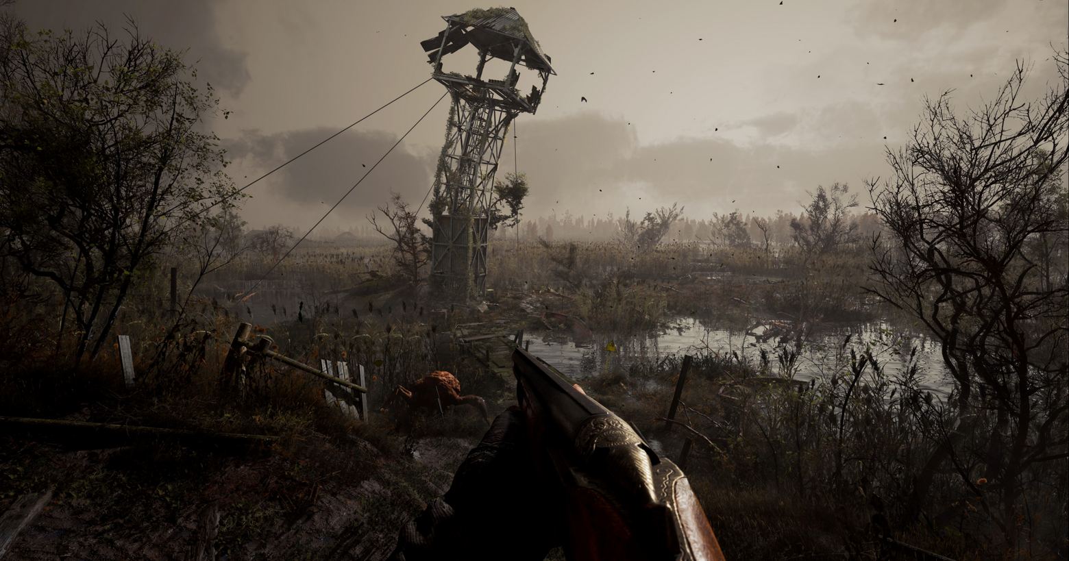 In Stalker 2 you can run through a huge post-apocalyptic open world. We also get to see this in a gameplay trailer. Here is a screenshot of it. In this one, we look from the player's point of view in first person view at a vast, gray, gloomy swampland that consists of many ponds and stagnant bushes. The player is holding a shotgun, which we see at the bottom center of the image. Right in front of him, a mutated creature is walking around on the swamp floor. It has a reddish skin color and resembles a large arachnid with several legs. To the right and left of the image are black dead trees in a crop. In the background, a tower scaffold rises from the swamp, bent to the right by the destruction and looking very damaged. The sky is light gray and overcast and we see many flying particles in the air.