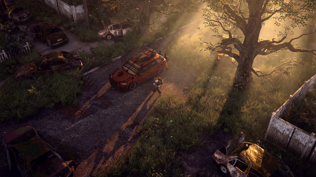 In this screenshot from The Last Stand: Aftermath the player is shown here in a long shot in the center of the image from an isometric perspective. He is in an urban environment during the day and is standing next to a red car in a courtyard, which is very atmospherically illuminated by the morning sun. The sun's rays come from the upper right and shine impressively through the branches of a tall tree, which we see in the upper right of the image. The player is currently aiming his rifle and carries a large brown backpack. Around him is a lot of green grass along with disturbed different cars and dirty white wooden fences.