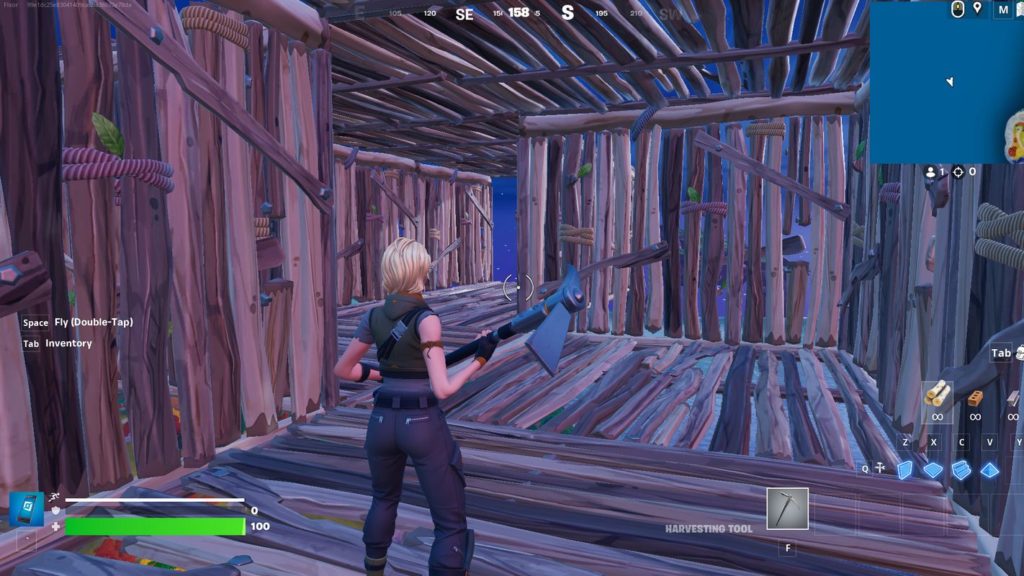 Here, the same character stands in a constructed wooden tunnel system that zigzags moderately horizontally forward. We can see the end of the tunnel in the background and the blue night sky in the distance. The player again has a pickaxe in his hand and looks into the background. Tunneling is also treated as an important method in many Fortnite building tips.