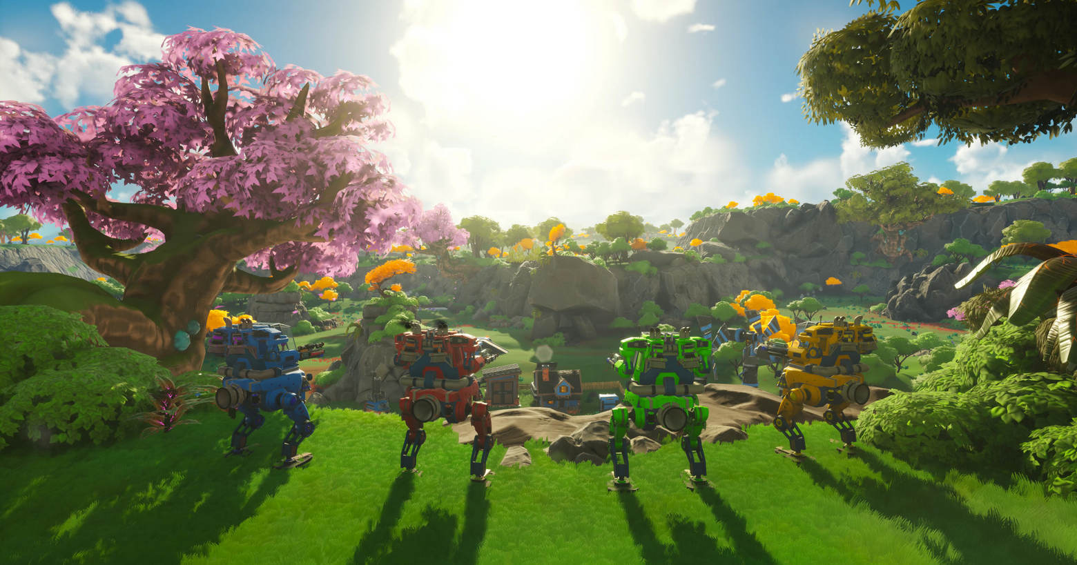 In this screenshot from Lightyear Frontier, we see four mechs of different colors standing side by side in a slight arc on a grassy field plateau and looking together toward the sun, which we see in the background at the top center of the image. The robots are shown in the foreground in a long shot in the lower half of the image. They are in a beautiful very green hilly landscape, covered with numerous green grasses, bushes, and trees. In the left foreground, next to the mechs, there is a large tree with pink leaves. In the background, we can see numerous yellow-leaved trees. The sun casts a very atmospheric and idyllic light on the robots and the blue cloudy sky underlines this relaxed scenario.