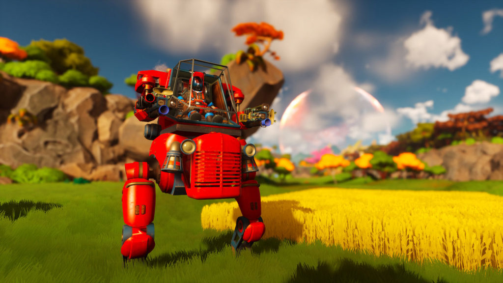 We see the same player from the previous screenshot. This time, however, we're looking at him from a distance, from a lower perspective, so that he's visible in the wide shot on the left. He stands next to a similar yellow rectangular Wheatfield and looks past us on the right. The red metallic robot has two large feet and a hood in the belly area that is reminiscent of a tractor. Above it, we see the player sitting in the glass cockpit, who has a red-blue suit and a black helmet. The arms of the mech resemble cannon barrels. In the background, we glimpse light brown rocks, green plants, and yellow-leaved trees in the blur. Above we see the blue sky with white clouds.