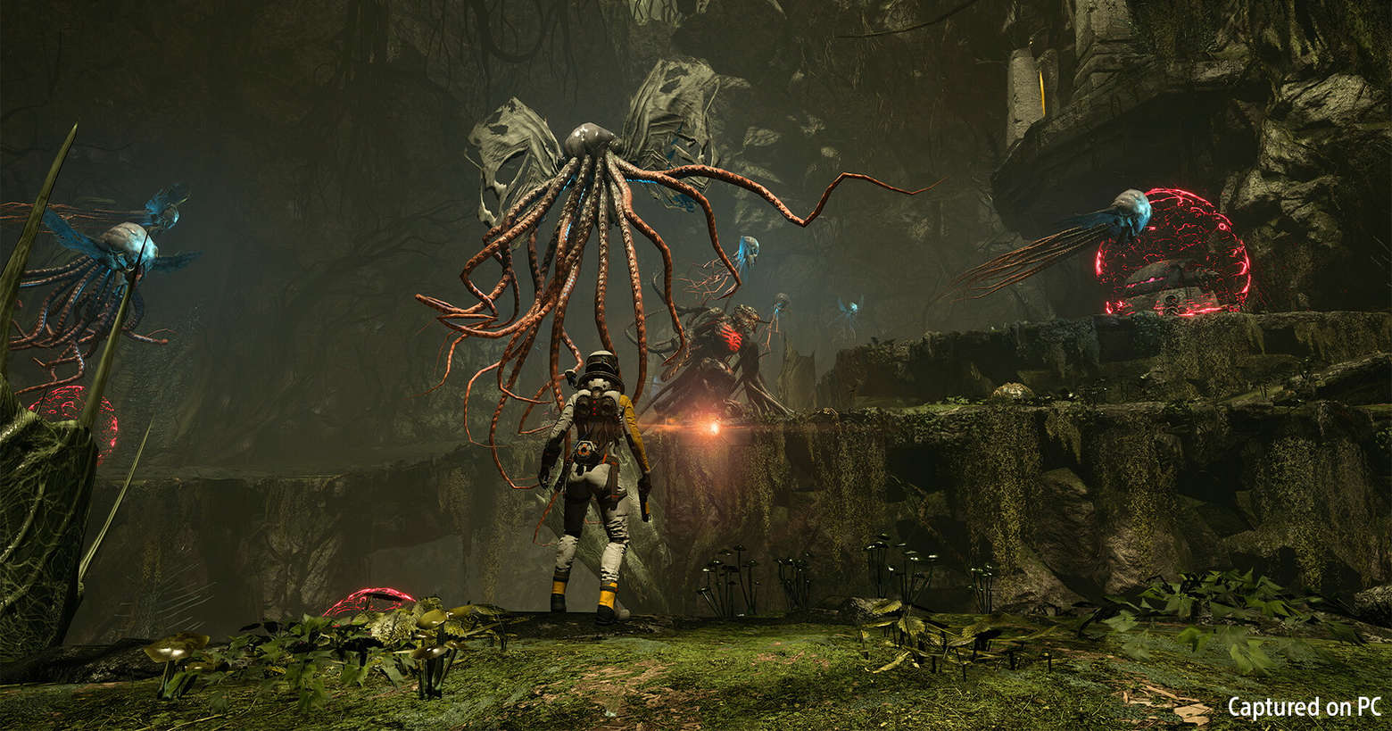 The main character from Returnal faces giant floating octopus-like creatures in a cave. The game is also available for PC as of today.
