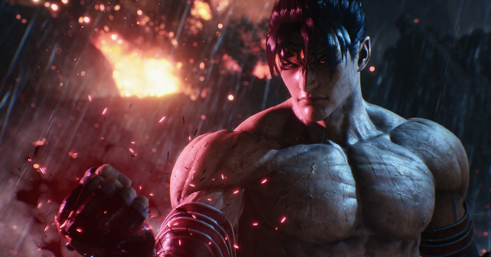 In this screenshot from Tekken 8, we catch a glimpse of a playable character in the near. He is in a harsh dark and rainy environment. The character has a muscular free torso and black hair tied back. He clenches his right hand into a fist, which he scowls at, with red sparks coming out of it. At the same time, a kind of explosion takes place in the back left, so that his back and the left side of his face are illuminated in red. The game doesn't have a release date yet, but there are already several gameplay trailers that also show many characters.